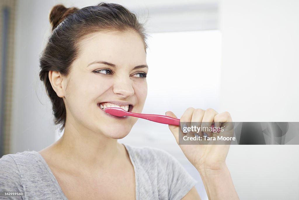 Woman brushing teeth in bathroom