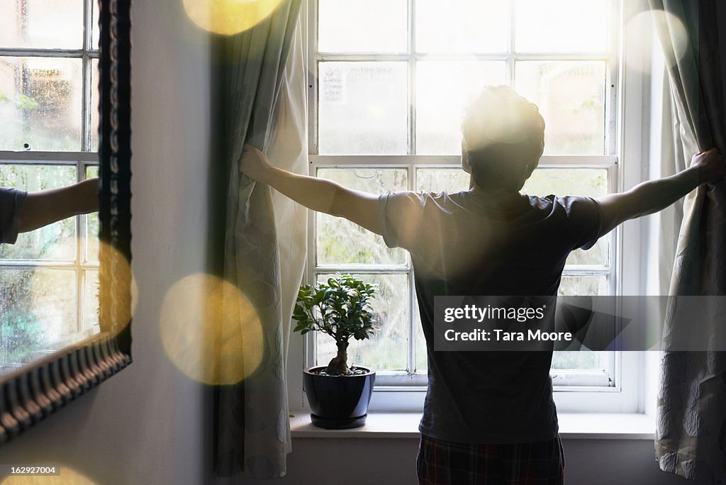 Man opening curtains in the morning