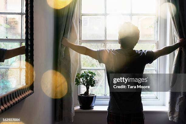 man opening curtains in the morning - sunlight imagens e fotografias de stock