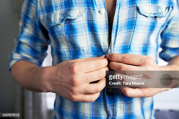 man doing up buttons on shirt - abrochar fotografías e imágenes de stock