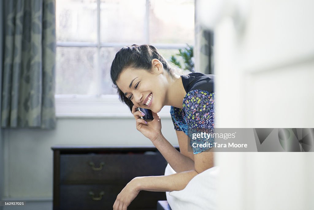 Woman on bed smiling with mobile phone