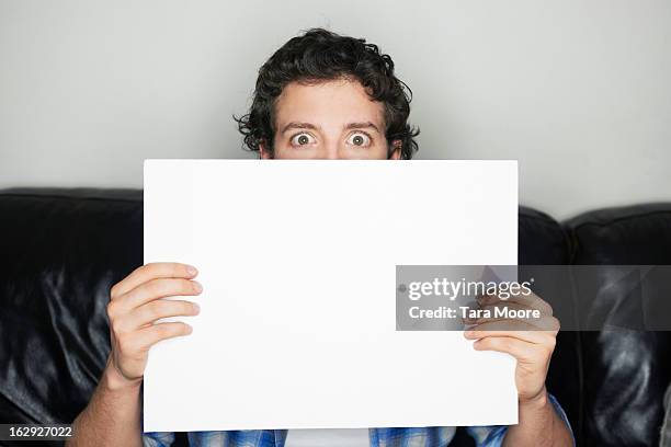 man looking wide-eyed holding blank sign - person holding blank sign stock-fotos und bilder