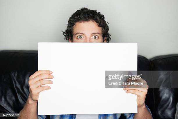 man looking wide-eyed holding blank sign - placard foto e immagini stock