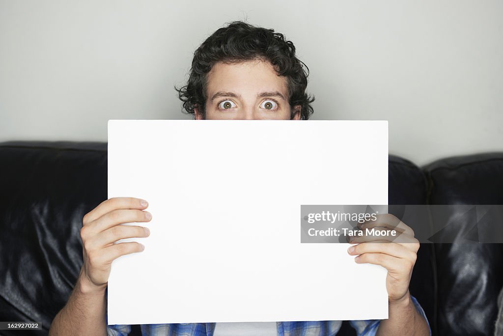 Man looking wide-eyed holding blank sign