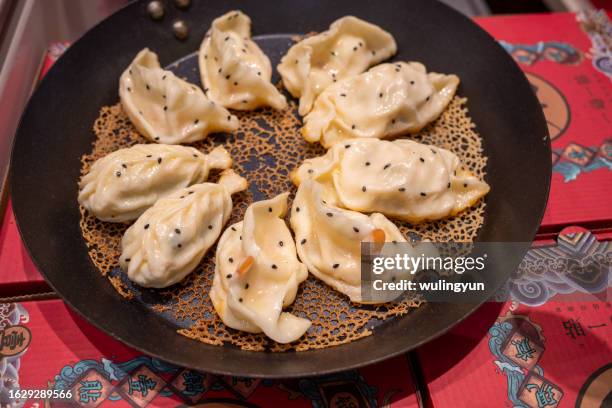 fried dumplings in cooking pan - chinese dumpling stock pictures, royalty-free photos & images