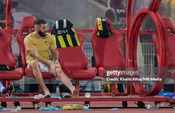 Karim Benzema of Al-Ittihad holds his knee whilst sitting on the substitute's bench after receiving an injury during the Saudi Pro League match at...