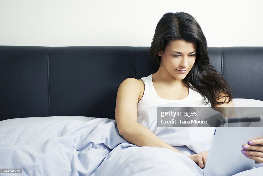 Woman in bed using digital tablet