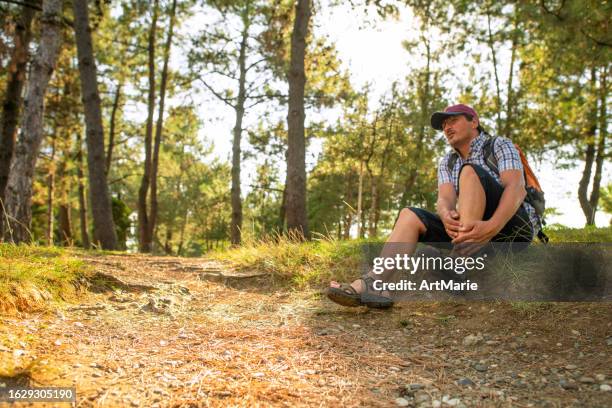 man suffering from pain in ankle while walking in a forest or park - sprain stock pictures, royalty-free photos & images