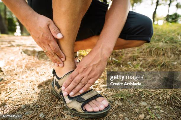 man suffering from pain in ankle while walking in a forest or park - menselijke voet stockfoto's en -beelden