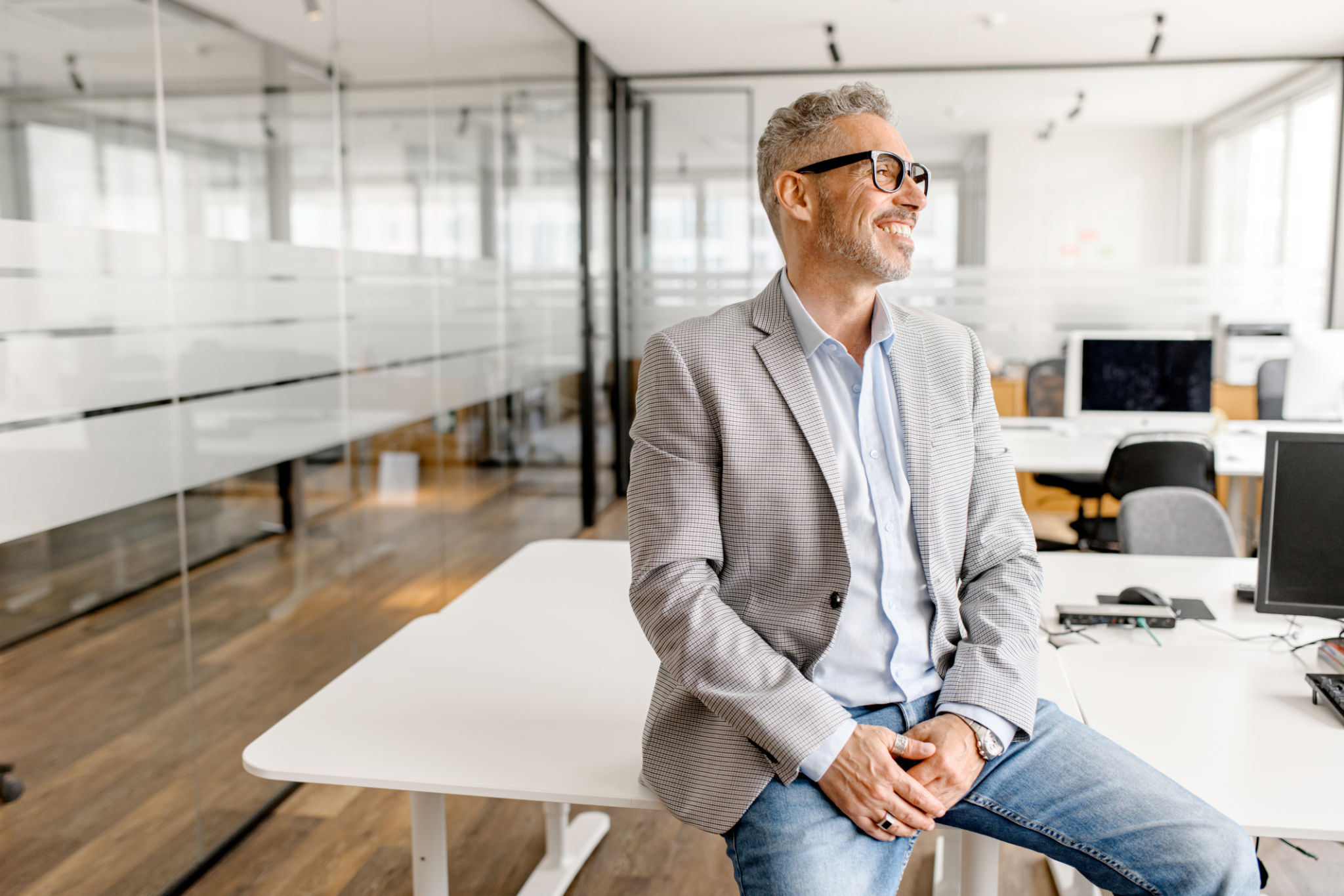 Serene modern middle aged businessman in formal wear leaned on the desk looking away Serene modern middle aged businessman in formal wear leaned on the desk looking away