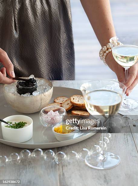 woman holding glass of wine & serving caviar - kaviaar stockfoto's en -beelden