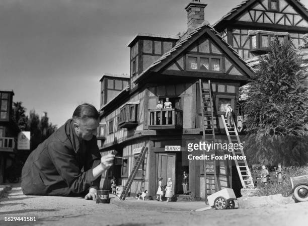 Maintenance man putting the finishing touches to a timber-framed 'building' at Bekonscot Model Village in Beaconsfield, Buckinghamshire, England,...