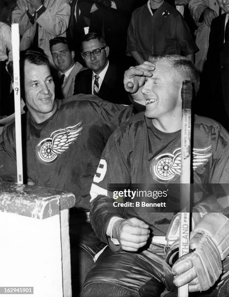 Gordie Howe of the Detroit Red Wings pats the head of his teammate Billy McNeill as they sit on the bench after Howe scored the 545th goal of his...