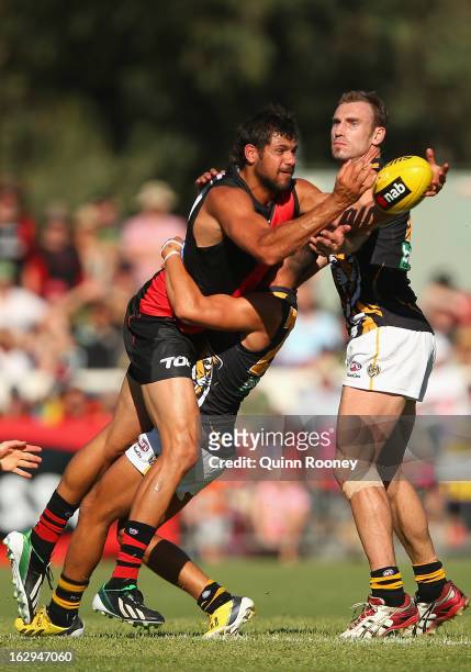Patrick Ryder of the Bombers handballs whilst being tackled during the round two AFL NAB Cup match between the Essendon Bombers and the Richmond...