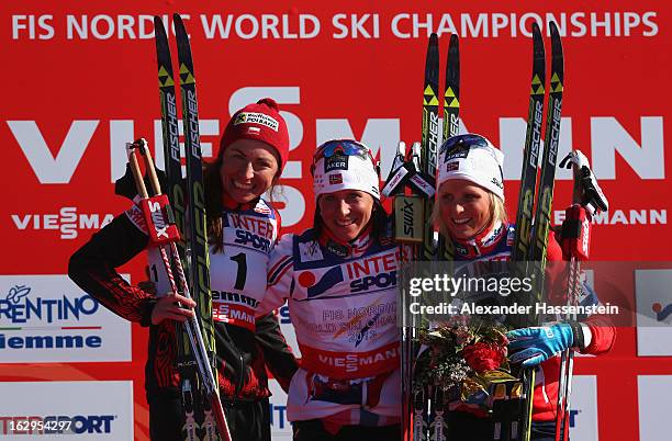 Marit Bjoergen of Norway celebrates First place on the podium with Second placed Justyna Kowalczyk of Poland and Third placed Therese Johaug of...