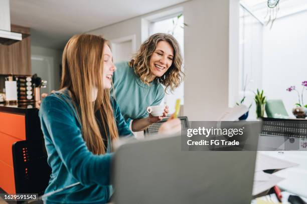mother helping daughter studying at home - candid girls stock pictures, royalty-free photos & images