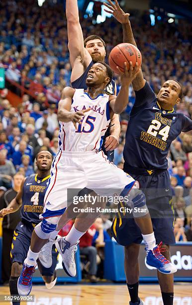 Kansas Jayhawks guard Elijah Johnson drives to the basket under West Virginia Mountaineers forward Deniz Kilicli and West Virginia Mountaineers...