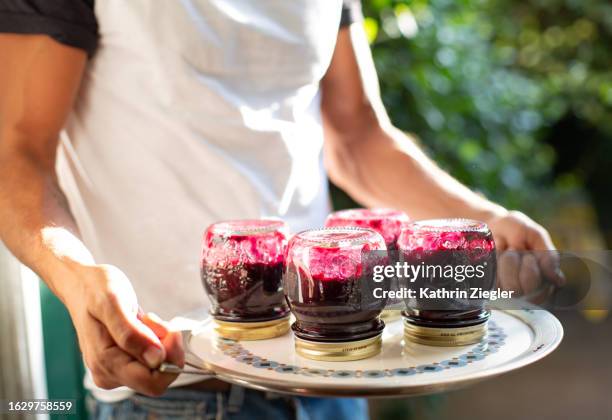 man holding a tray with jars of freshly made blackberry marmalade - marmelade stock-fotos und bilder