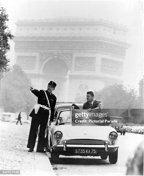 French Policeman aid tourists outside Arc de Triomphe in Paris, France, 1955.