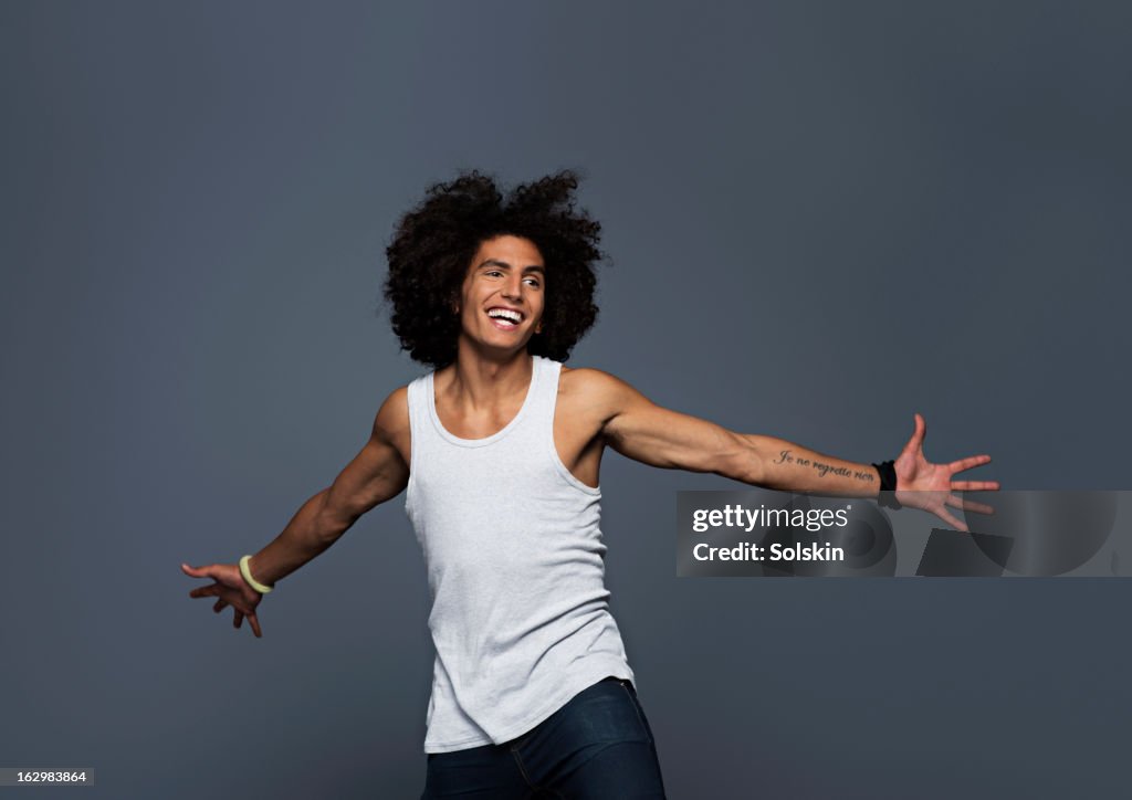 Young man stretching out arms, studio background