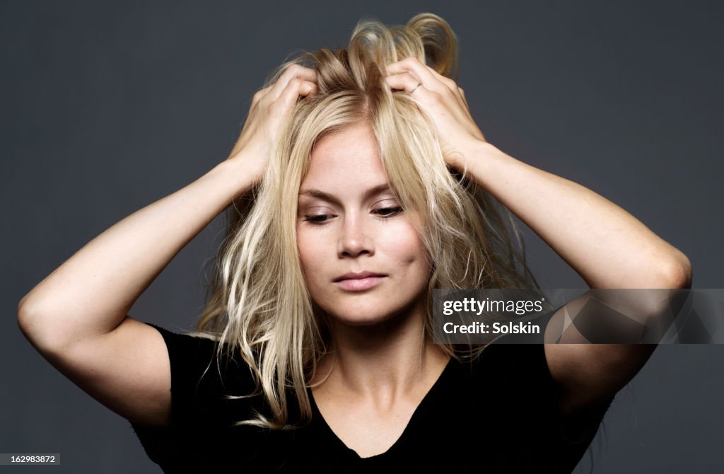 Woman holding hands to her hair, studio background