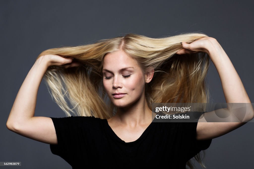 Woman with hands in her hair, studio background