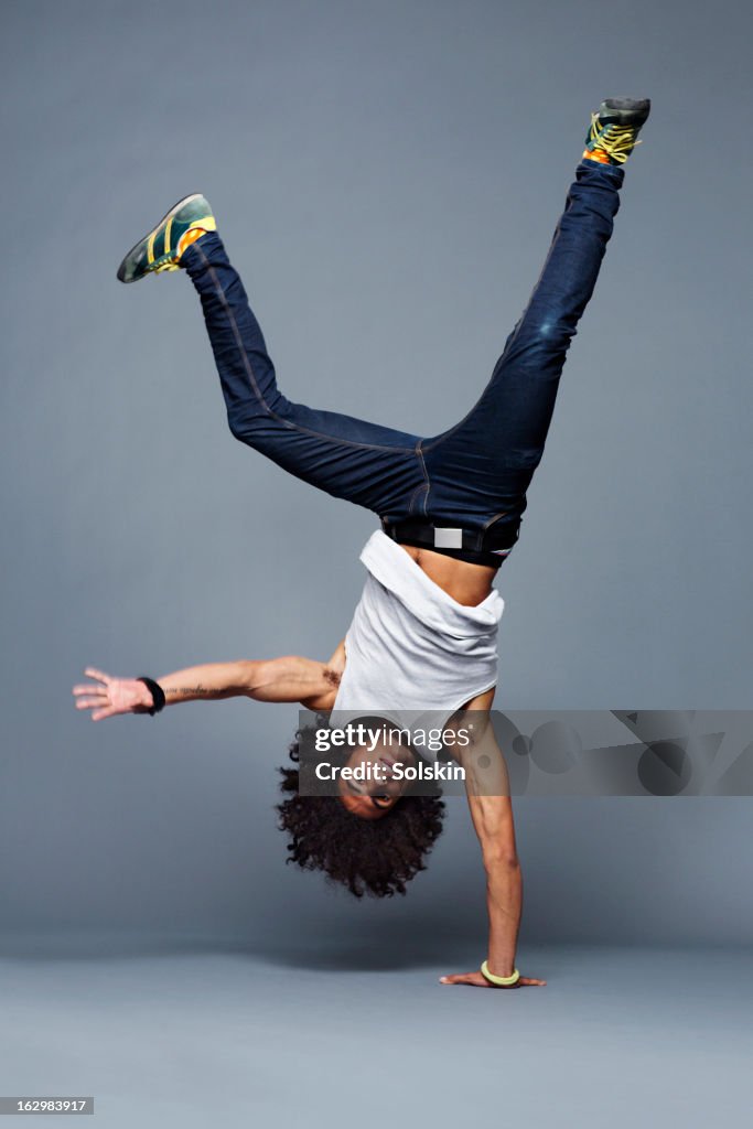 Man making one arm handstand, studio background