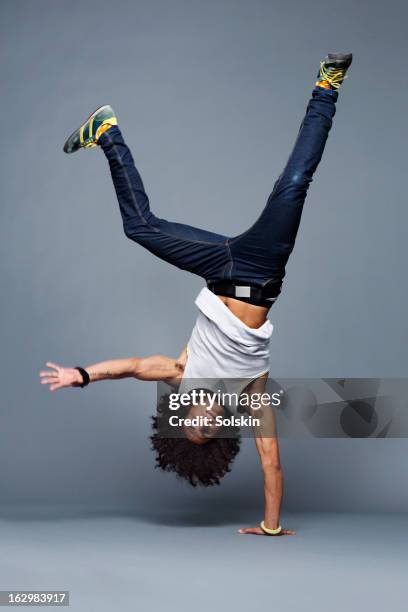man making one arm handstand, studio background - fare la verticale sulle mani foto e immagini stock