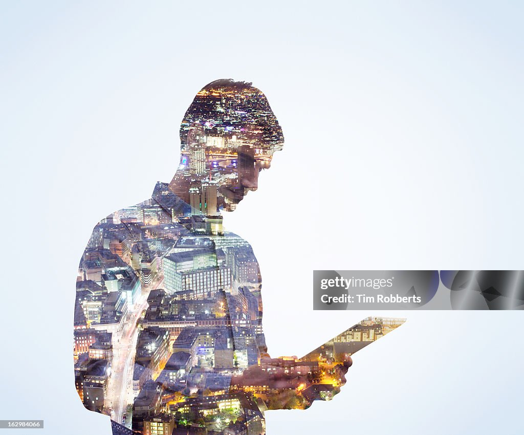 Man using digital tablet with city view at night.