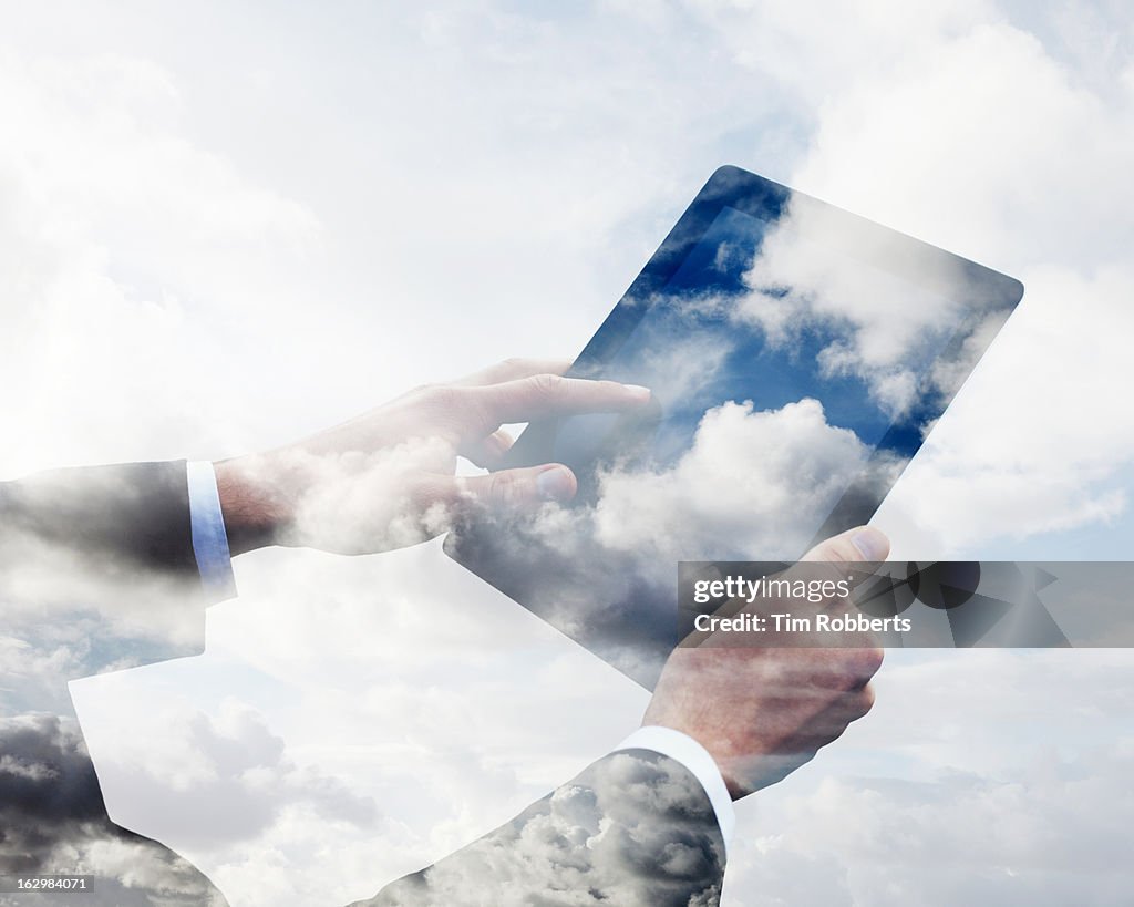 Business man using tablet with clouds.