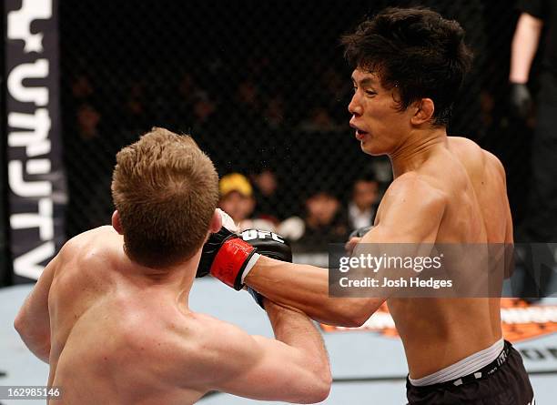 Takeya Mizugaki punches Bryan Caraway in their bantamweight fight during the UFC on FUEL TV event at Saitama Super Arena on March 3, 2013 in Saitama,...