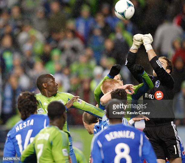 Eddie Johnson, of the Seattle Sounders looks on as Troy Perkins, goalie of Montreal Impact punches the ball away in the second half at CenturyLink...