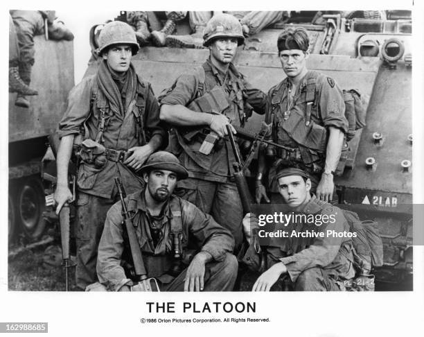 Charlie Sheen, Tom Berenger, Willem Dafoe and two other men pose in front of a tank in a publicity portrait for the film 'Platoon', 1986.