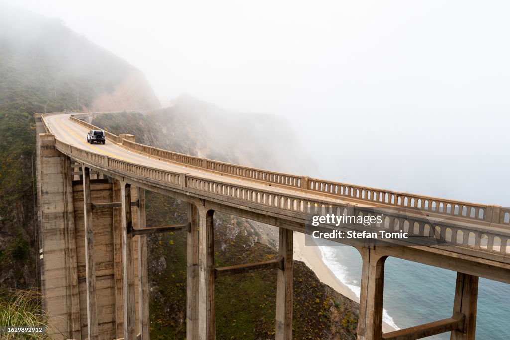 Scenic fog raising above the bridge at Big Sur California by Pacific Coast Highway, Bixby Creek Bridge, Rocky Creek Bridge