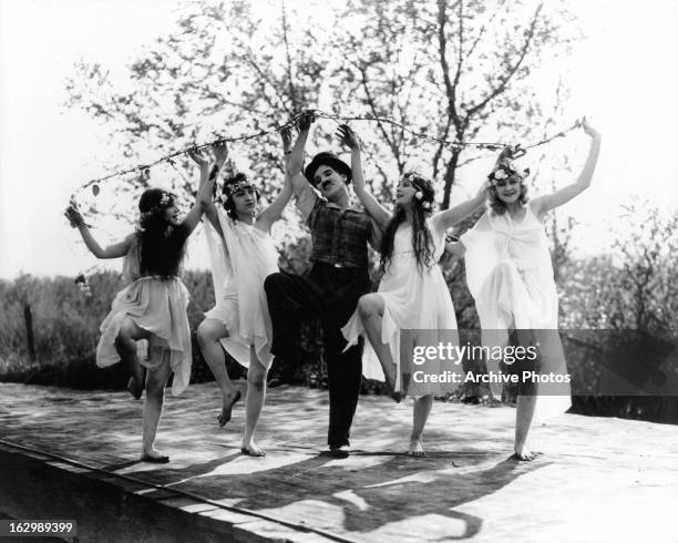 Charles Chaplin dances with the wood nymphs in a scene from the film 'Sunnyside', 1919.