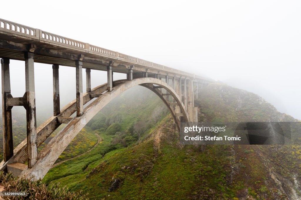 Scenic fog raising above the bridge at Big Sur California by Pacific Coast Highway, Bixby Creek Bridge, Rocky Creek Bridge