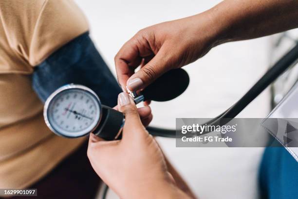 mano de enfermera tomando la presión arterial de un paciente - indicador de presión sanguínea fotografías e imágenes de stock
