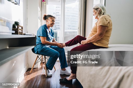 Nurse massaging a senior woman's foot at home Nurse massaging a senior woman's foot at home