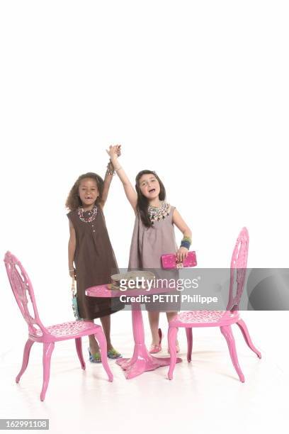 Gifts For Mother'S Day. Photo studio : deux fillettes jouant à la maman avec de gauche à droite, Angelina en robe trois trous en lin chocolat bordée...