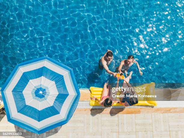 group of diverse friend drinking alcohol, having a pool party together. - fiesta de piscina fotografías e imágenes de stock