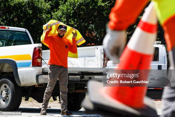 Altadena, CA, Monday, August 28, 2023 - An LA County road crewmember Estevan Robles seeks shade from his uniform as crews wrap up after working to...