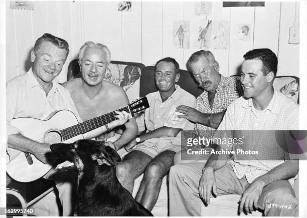 James Cagney plays a guitar as William Powell, Henry Fonda, Ward Bond, and Jack Lemmon enjoy themselves during a break from shooting the film 'Mister...