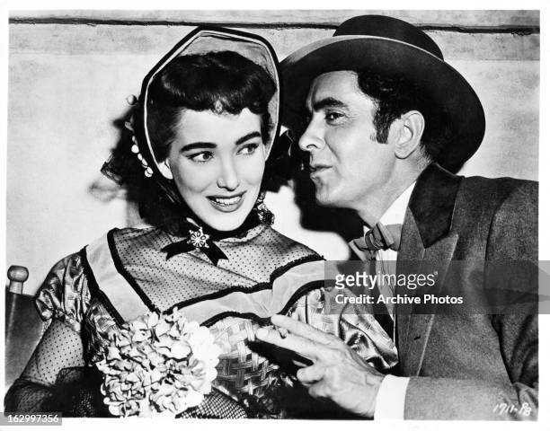 Julie Adams is whispered to by Tyrone Power on set of the film 'The Mississippi Gambler', 1953.