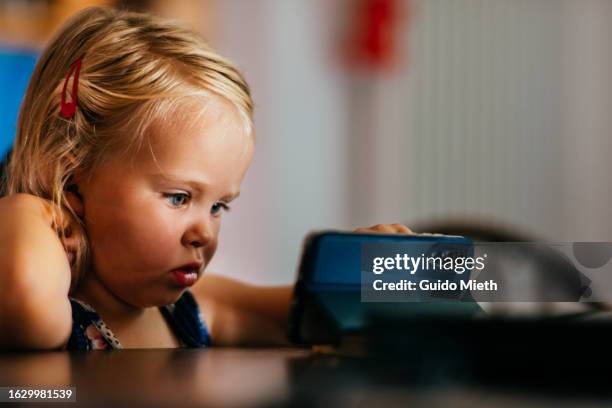 little girl using mobile phone at home. - mobile game stock pictures, royalty-free photos & images