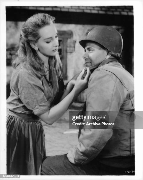 Taina Elg fastens a star on Glenn Ford's colar in a scene from the film 'Imitation General', 1958.