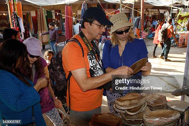 Tourists from France buy Sanskruti Foodware products from a stall during the final day of Basant Utsav exhibition at Ramlila Ground Noida Stadium in...