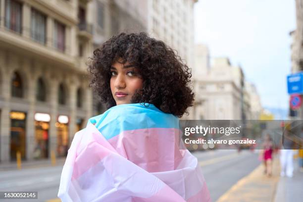 transgender person wrapping with a transgender flag - transgender stock-fotos und bilder