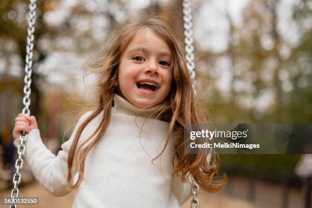 mädchen schaukelt auf einem spielplatz - schaukel stock-fotos und bilder
