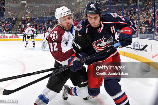 Chuck Kobasew of the Colorado Avalanche and Jared Boll of the Columbus Blue Jackets battle for position on a loose puck in the first period on March...