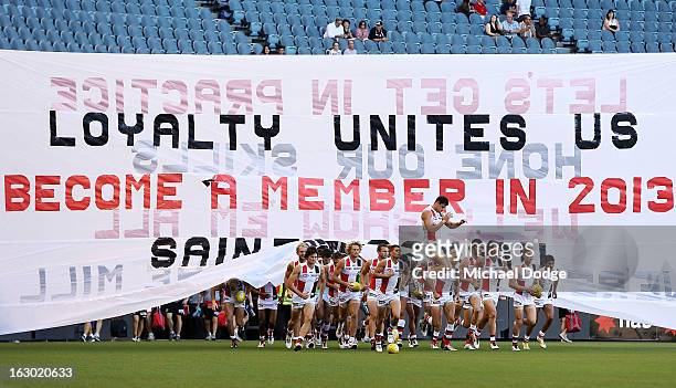 The St.Kilda Saints players run through the banner during the round two AFL NAB Cup match between the St Kilda Saints and the Sydney Swans at Etihad...